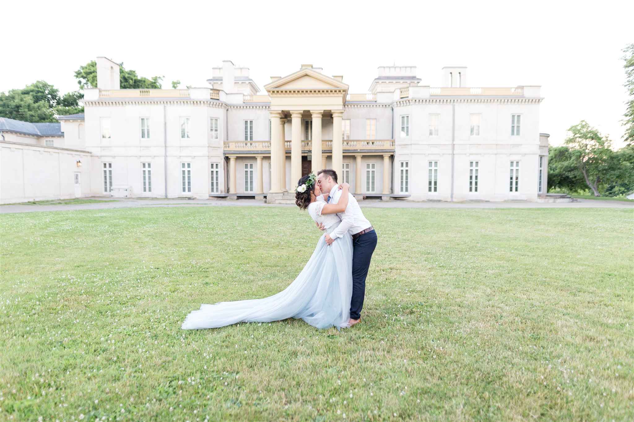 couple holding each other close in front of dundurn castle wearing suit and dress
